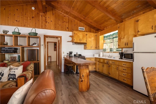 kitchen featuring white refrigerator, beam ceiling, hardwood / wood-style floors, and sink