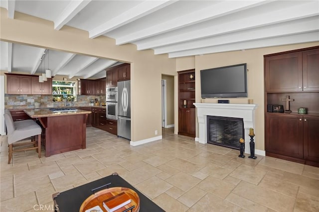 kitchen with pendant lighting, a center island, a kitchen bar, beamed ceiling, and light stone counters