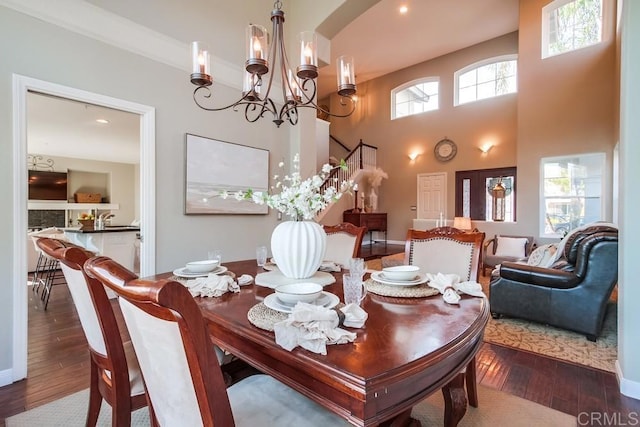 dining space with an inviting chandelier, crown molding, dark hardwood / wood-style floors, and a high ceiling