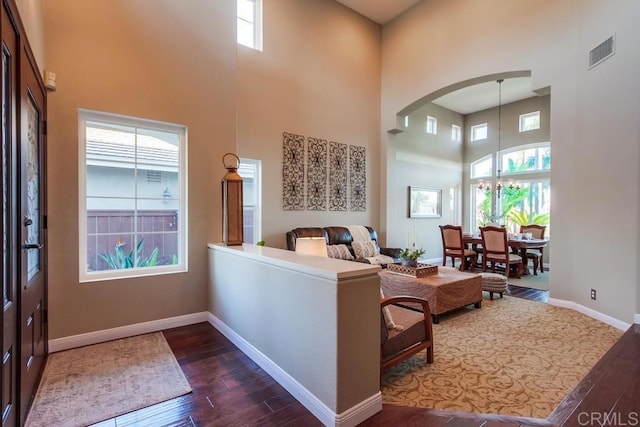 living room featuring a towering ceiling, a wealth of natural light, and dark wood-type flooring