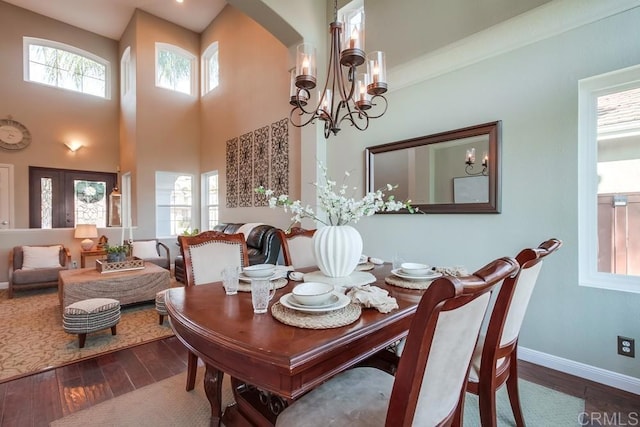 dining space featuring a towering ceiling, a notable chandelier, and dark hardwood / wood-style flooring