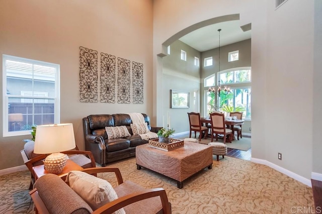 living room featuring a notable chandelier, light carpet, and a high ceiling