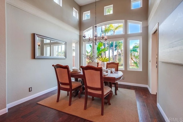 dining room featuring a towering ceiling, dark hardwood / wood-style floors, and a chandelier