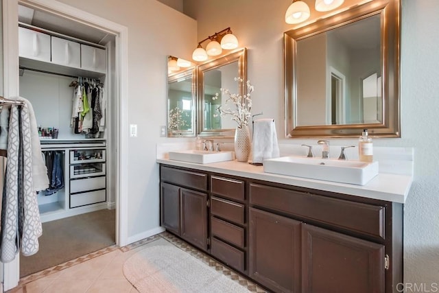 bathroom featuring tile patterned flooring, a sink, a spacious closet, and double vanity