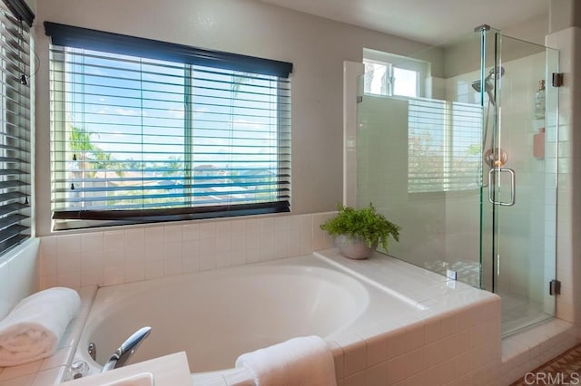 full bathroom with a shower stall and a bath