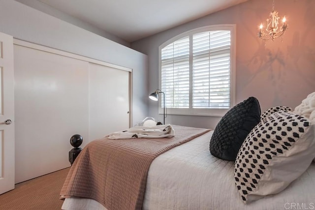 carpeted bedroom with a chandelier and a closet