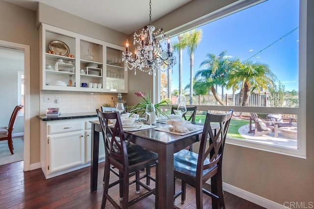 dining room with dark wood-style flooring, an inviting chandelier, and baseboards