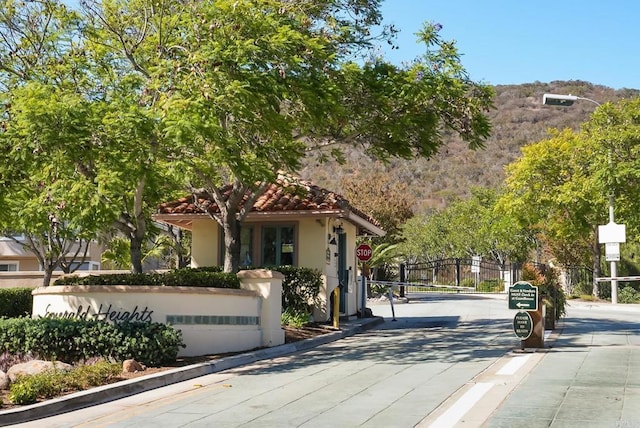 view of road featuring a gated entry, curbs, traffic signs, a gate, and a mountain view