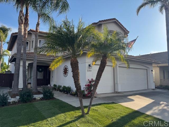 view of front of home with a garage, driveway, a front lawn, and stucco siding