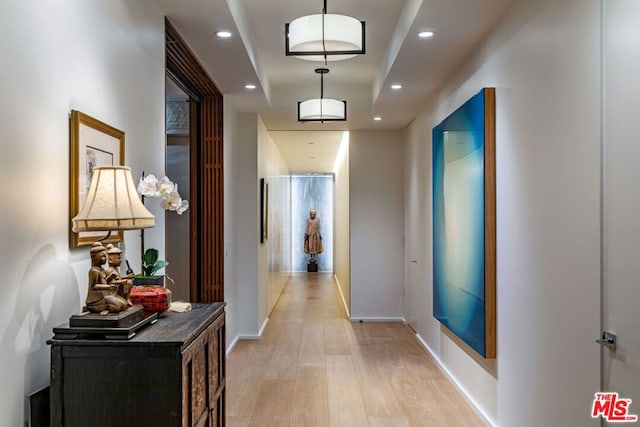 hallway featuring light hardwood / wood-style floors and a raised ceiling