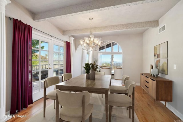 dining space with light hardwood / wood-style floors, a wealth of natural light, beam ceiling, and a chandelier