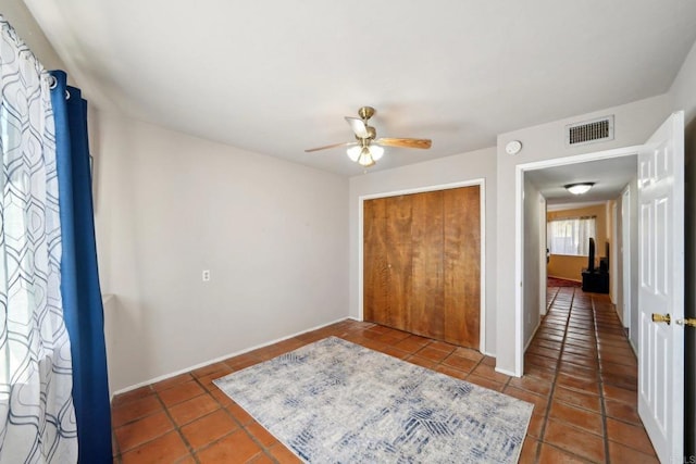 bedroom featuring ceiling fan, a closet, and dark tile patterned flooring