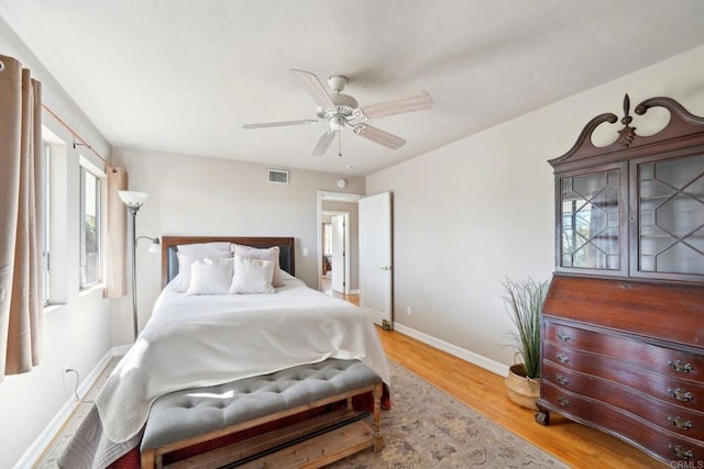 bedroom with ceiling fan, wood-type flooring, and multiple windows