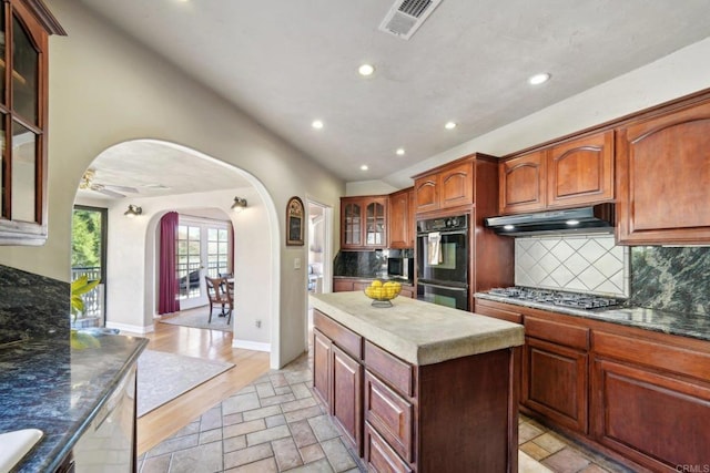 kitchen with dishwashing machine, black double oven, backsplash, stainless steel gas cooktop, and ceiling fan