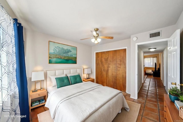 tiled bedroom with ceiling fan and a closet