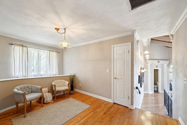 sitting room with hardwood / wood-style floors, ornamental molding, and lofted ceiling with beams