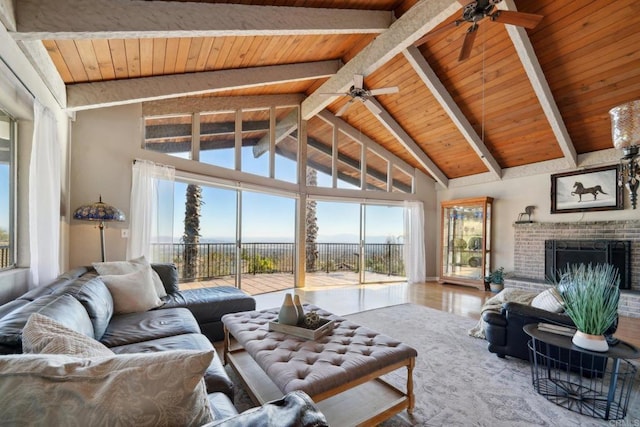 living room featuring beam ceiling, wood ceiling, plenty of natural light, and a fireplace