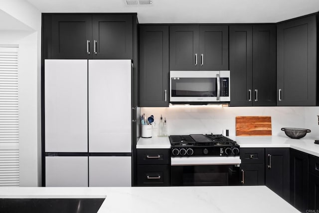 kitchen with white refrigerator, tasteful backsplash, and black range with gas cooktop