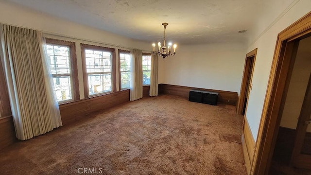 unfurnished dining area with carpet, a chandelier, and plenty of natural light