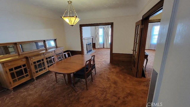 dining room with dark colored carpet and ornamental molding