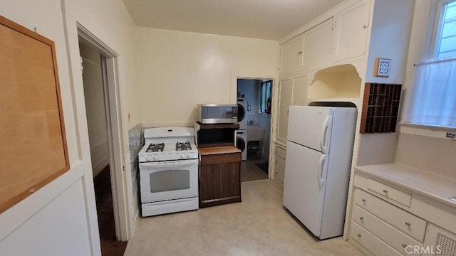 kitchen featuring white appliances, white cabinets, and washer / dryer