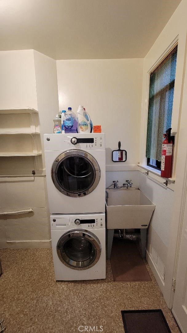 laundry area with stacked washer and dryer and sink