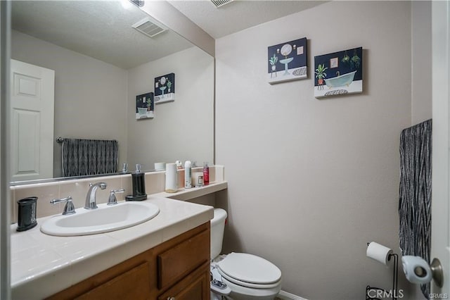 bathroom featuring a textured ceiling, toilet, and vanity