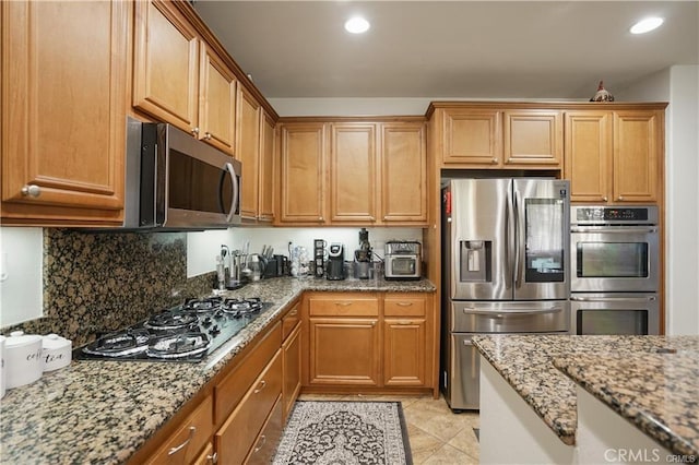 kitchen featuring light stone countertops, light tile patterned floors, stainless steel appliances, and tasteful backsplash