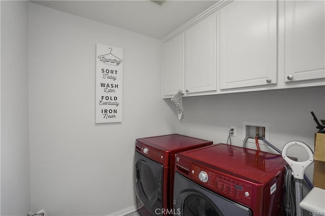 clothes washing area with washer and dryer and cabinets