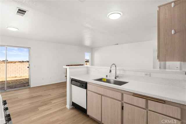 kitchen featuring light brown cabinetry, a wealth of natural light, white dishwasher, and sink