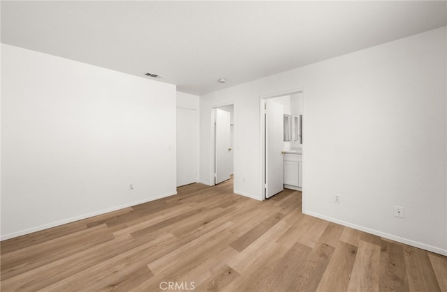 unfurnished bedroom featuring light wood-type flooring and ensuite bath