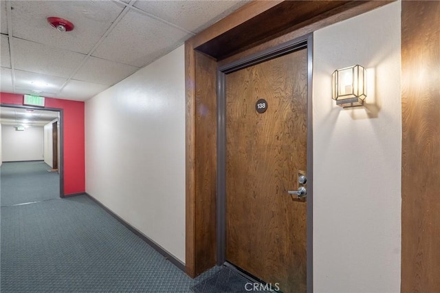 hall with carpet and a paneled ceiling