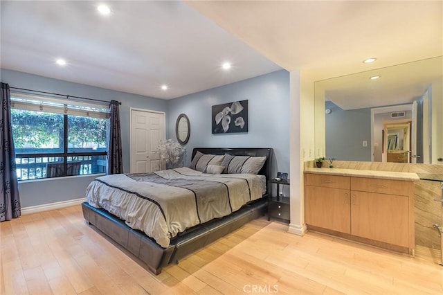 bedroom featuring ensuite bath and light hardwood / wood-style floors