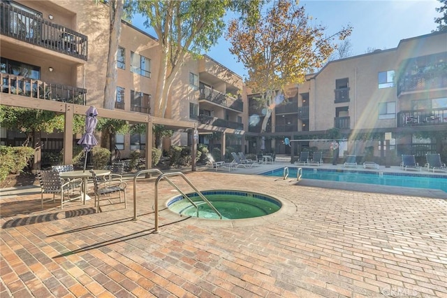 view of swimming pool featuring a hot tub and a patio