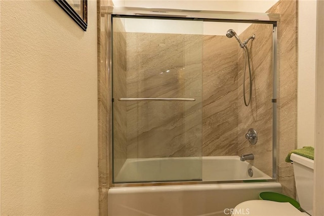 bathroom with combined bath / shower with glass door and toilet