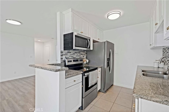 kitchen with light tile patterned floors, white cabinetry, appliances with stainless steel finishes, decorative backsplash, and sink