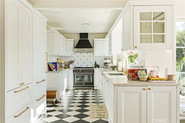 kitchen featuring white cabinets, decorative backsplash, range with gas stovetop, and wall chimney exhaust hood