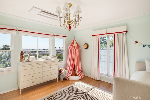 bedroom with crown molding, a chandelier, and light wood-type flooring