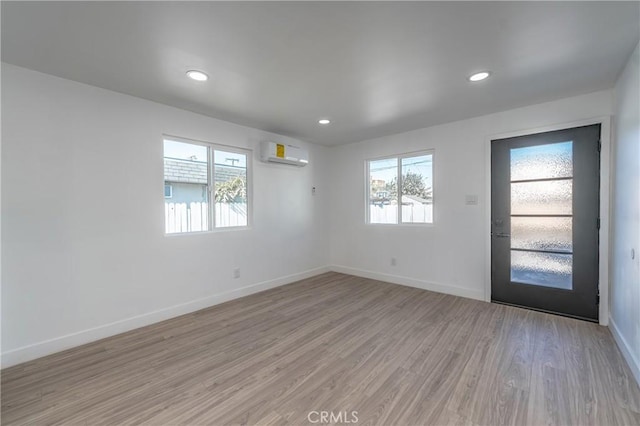 empty room featuring a wall mounted AC and light wood-type flooring