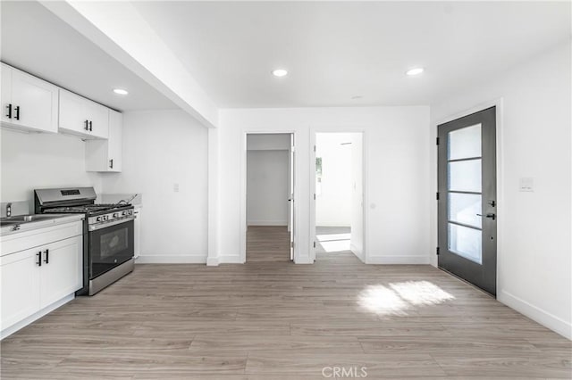 kitchen featuring light hardwood / wood-style floors, white cabinetry, gas stove, and a healthy amount of sunlight