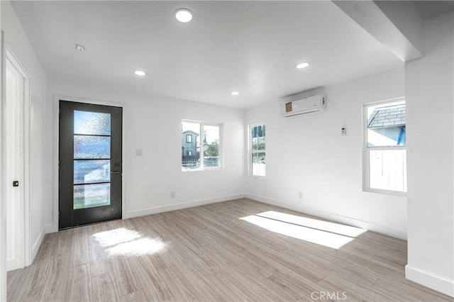 empty room featuring an AC wall unit and light hardwood / wood-style flooring