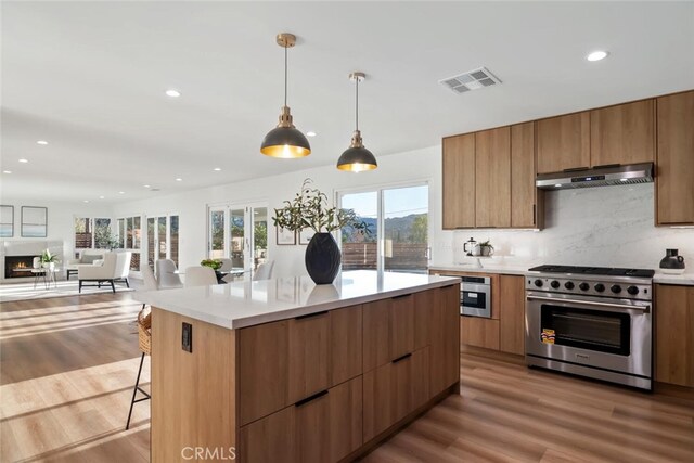 kitchen featuring pendant lighting, decorative backsplash, a wealth of natural light, a breakfast bar area, and high end stainless steel range