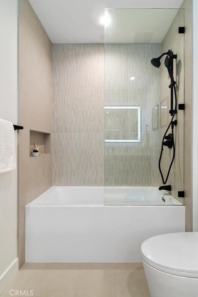 bathroom with toilet, tile patterned flooring, and tiled shower / bath combo