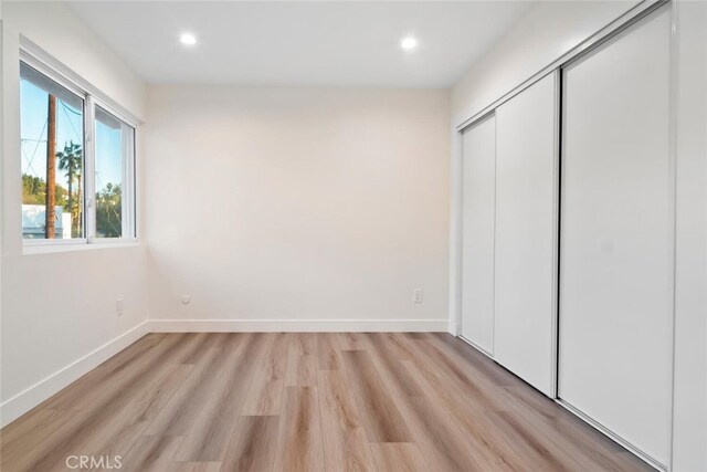 unfurnished bedroom with light wood-type flooring and a closet