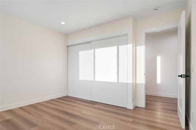 unfurnished bedroom with a closet and light hardwood / wood-style flooring