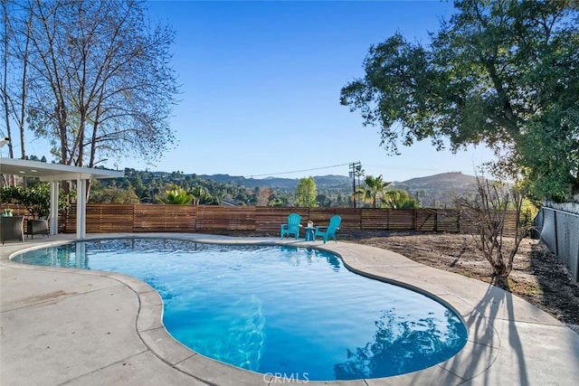 view of pool featuring a fenced in pool, a patio area, a fenced backyard, and a mountain view