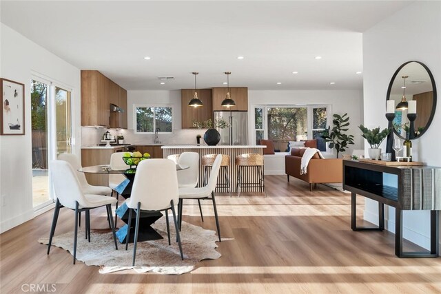 dining room with light hardwood / wood-style floors, sink, and a wealth of natural light