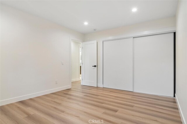 unfurnished bedroom with a closet and light wood-type flooring