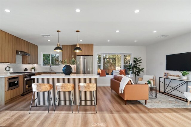 kitchen featuring a kitchen island, hanging light fixtures, plenty of natural light, a breakfast bar area, and stainless steel appliances