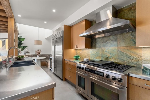 kitchen featuring stainless steel counters, decorative backsplash, sink, wall chimney exhaust hood, and high quality appliances